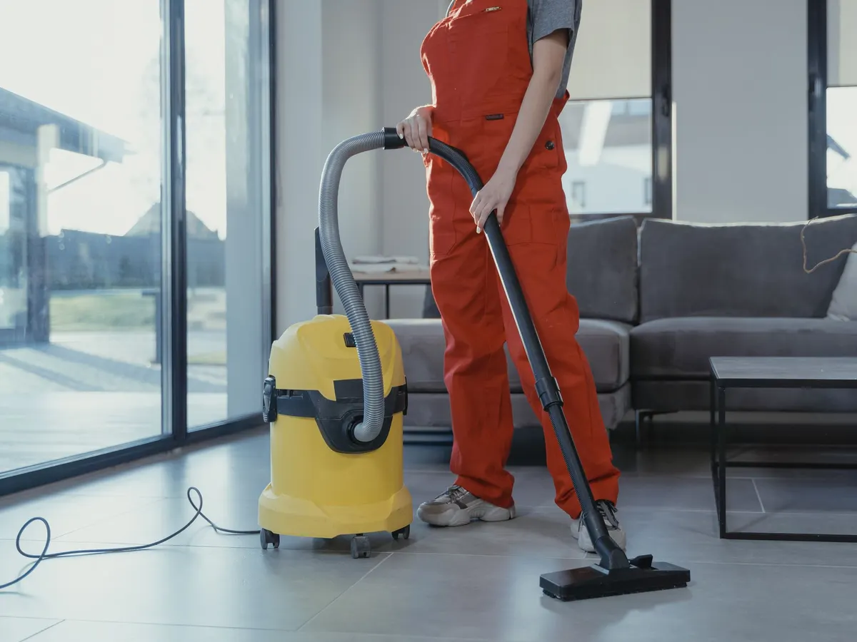 Cleaner vacuuming a bright living room